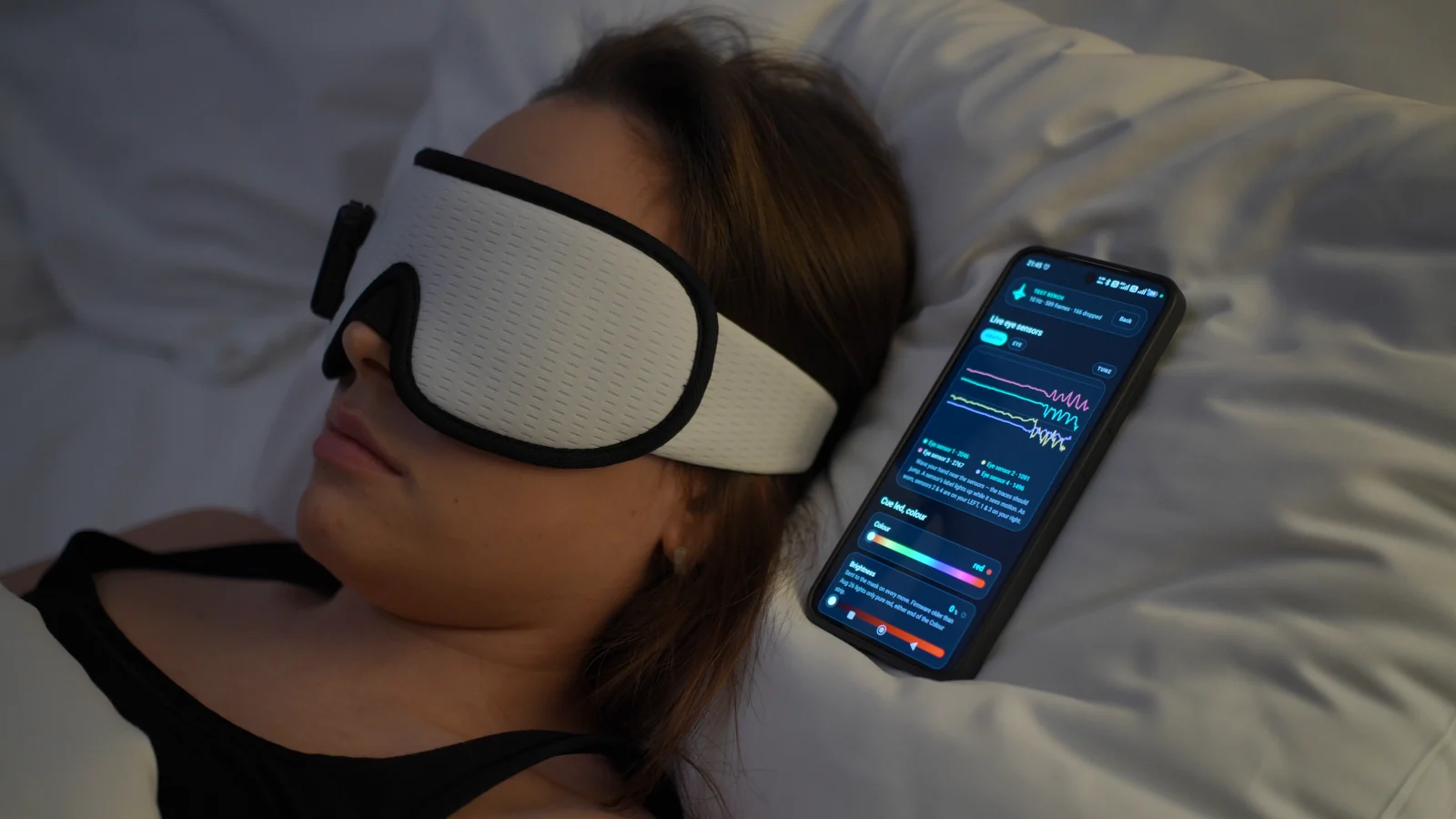 Awake demonstration: a person wearing the mask beside a phone showing live eye-sensor traces